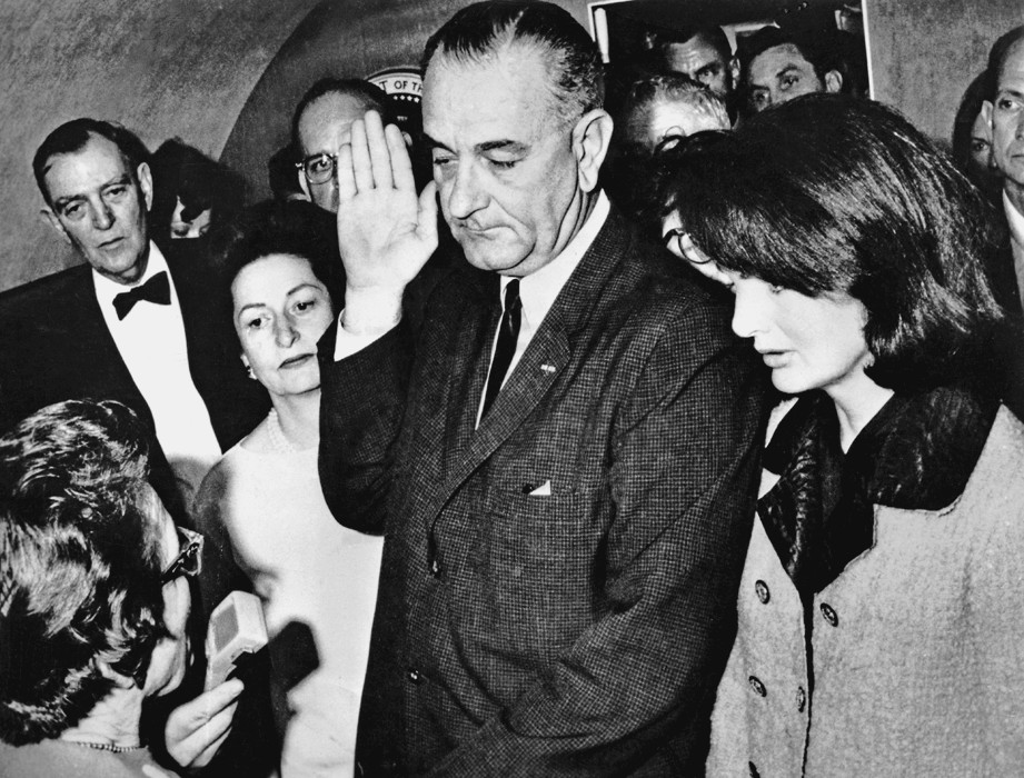 Figure 3-2: Johnson takes the oath of office aboard Air Force One, with Jackie Kennedy looking on.